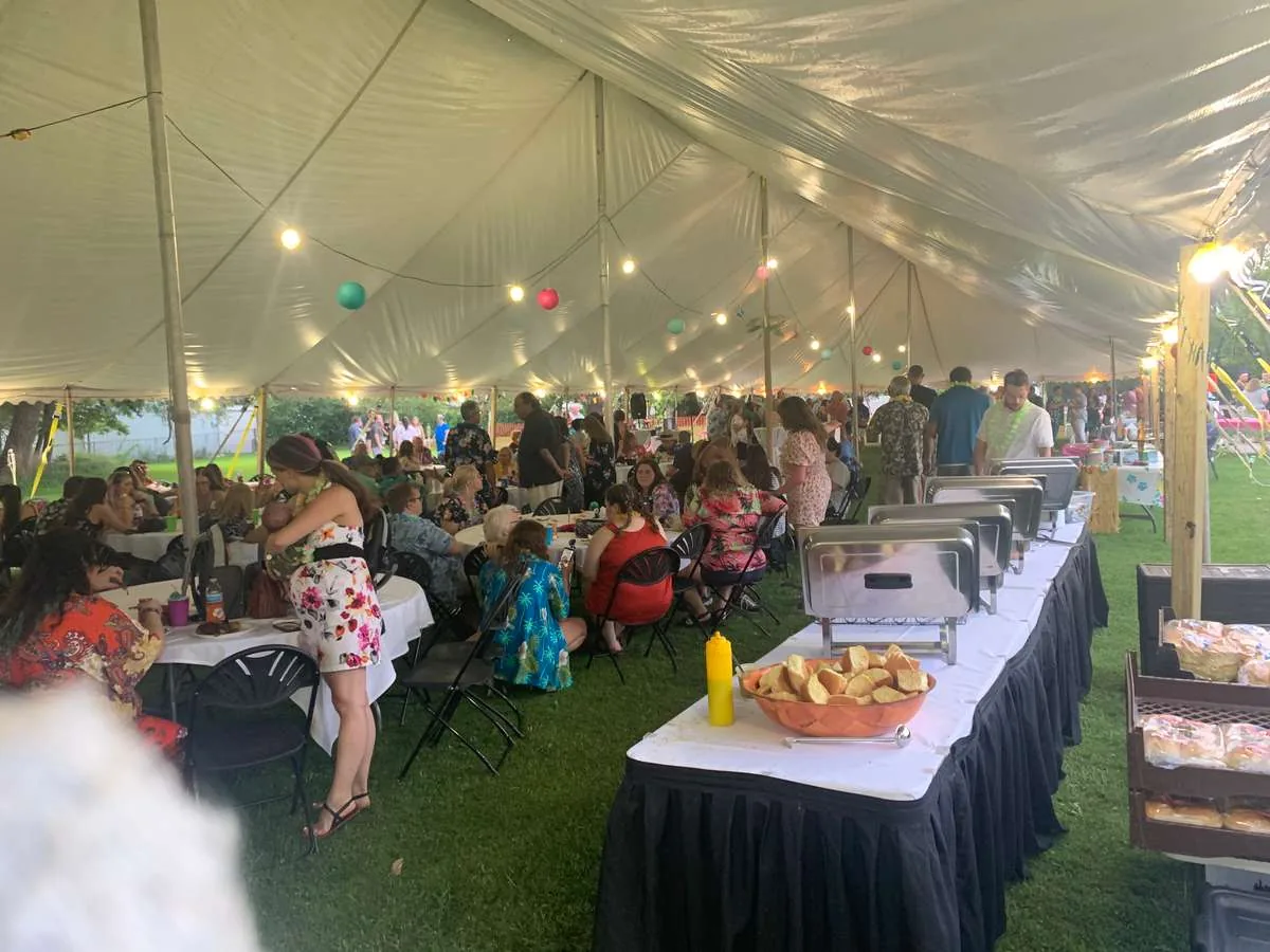 Guests dining and a buffet line set up under a large event tent
